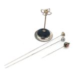 Silver plated hatpin stand with three hatpins including two silver examples, the stand 9.5cm high :