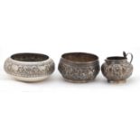 Two Indian silver bowls and a jug, each embossed with wild animals, the largest 12cm in diameter,