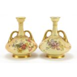 Pair of Royal Worcester blush ivory vases with twin handles, each decorated with flowers, numbered