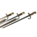 Three French military interest Gras bayonets, two with scabbards, various impressed marks, the
