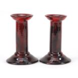 Pair of Royal Doulton flambe candlesticks by Charles Noke and Harry Nixon, each 14.5cm high :For