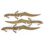 Three brass daggers with mythical animal design handles, each 40cm in length :For Further