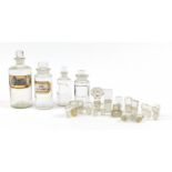 Four antique glass apothecary jars and extra stoppers, including two bottles with labels, the