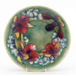 William Moorcroft pottery shallow bowl hand painted in the Orchid pattern onto a green ground,