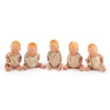 Five hand painted bisque porcelain dolls with articulated limbs, housed in a basket, each 7.5cm high