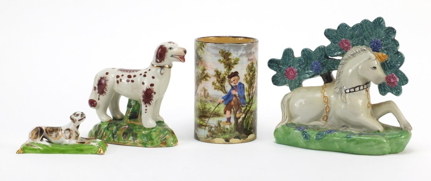 Three Staffordshire style animals and a cylindrical pot hand painted with a fisherman, the largest