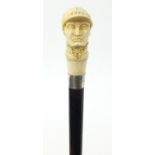 Good ebonised walking stick with carved ivory pommel in the form of jockey Fred Archer, having a