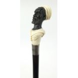 Good ebonised walking stick with carved ivory and horn pommel in the form of a blackamoor, having