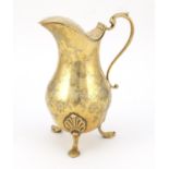 Silver gilt water jug with hinged lid, the body engraved with flowers and raised on three hoof feet,