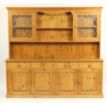 Large pine dresser fitted with two leaded glass doors and open plate rack above drawers and cupboard