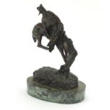 Patinated bronze figure of a cowboy on horseback in the style of Frederick Remington, raised on an