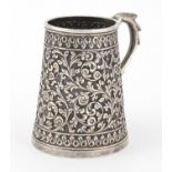 Indian unmarked silver tankard of conical form, profusely embossed with flowers and foliage, 9cm
