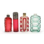 Four Victorian glass scent bottles including a cranberry example with embossed silver lid, the