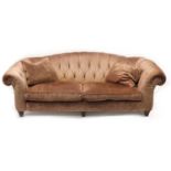 Pink upholstered Chesterfield type three seater settee with two cushions on turned wooden feet, 82cm