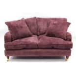 Purple upholstered two seater settee with two extra cushions on turned wooden feet with brass
