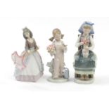 Three Lladro figurines including a girl seated with a vase of flowers and young girl with