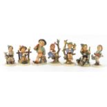 Seven Goebel Hummel figures with paper labels including Merry Wanderer, Apple Tree Boy, Apple Tree