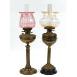 Two brass oil lamps with reeded columns and floral glass shades, one converted for electric use
