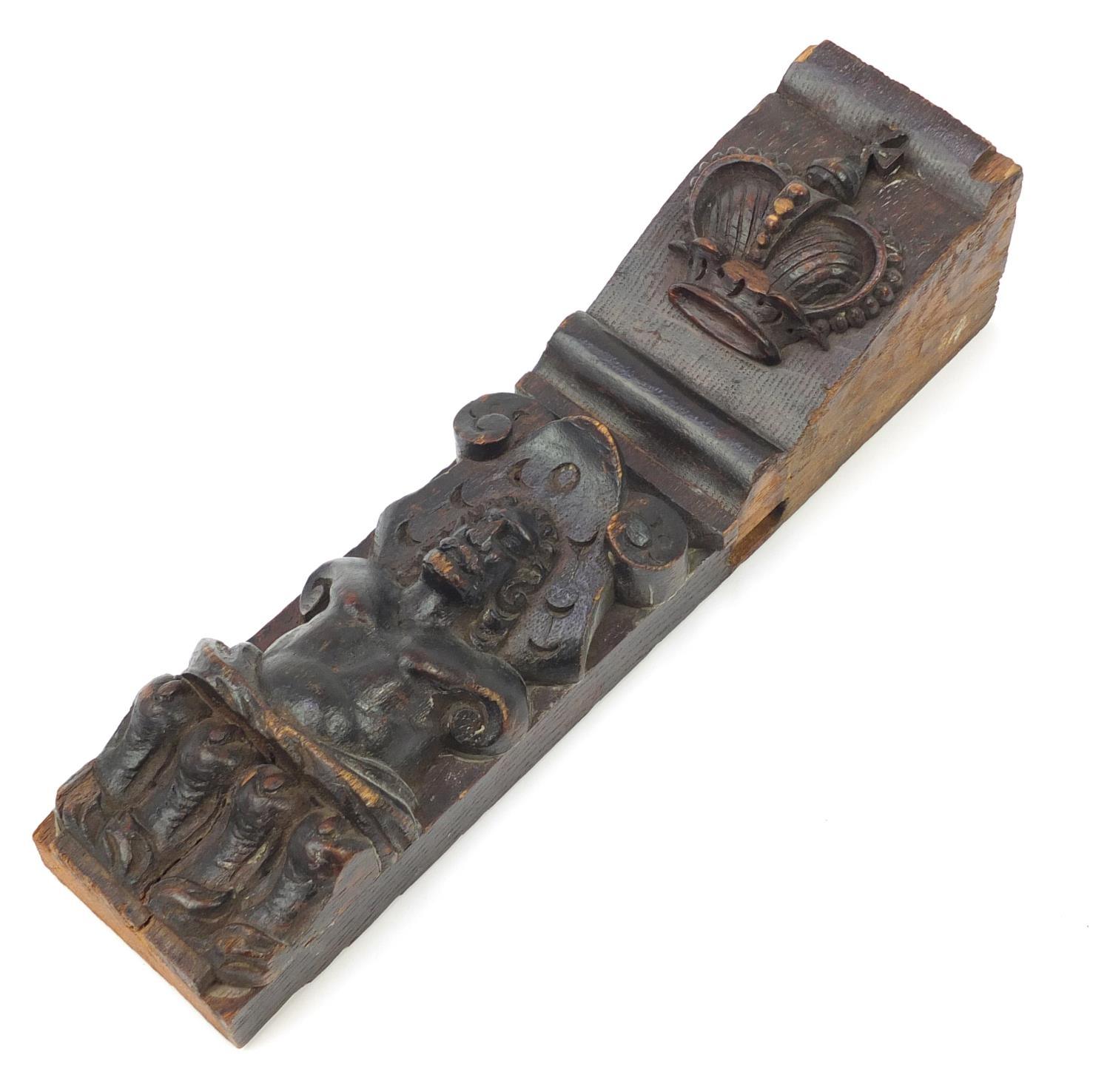 Early 17th century oak bracket carved with a gentleman in a hat and a royal crown, 31cm in