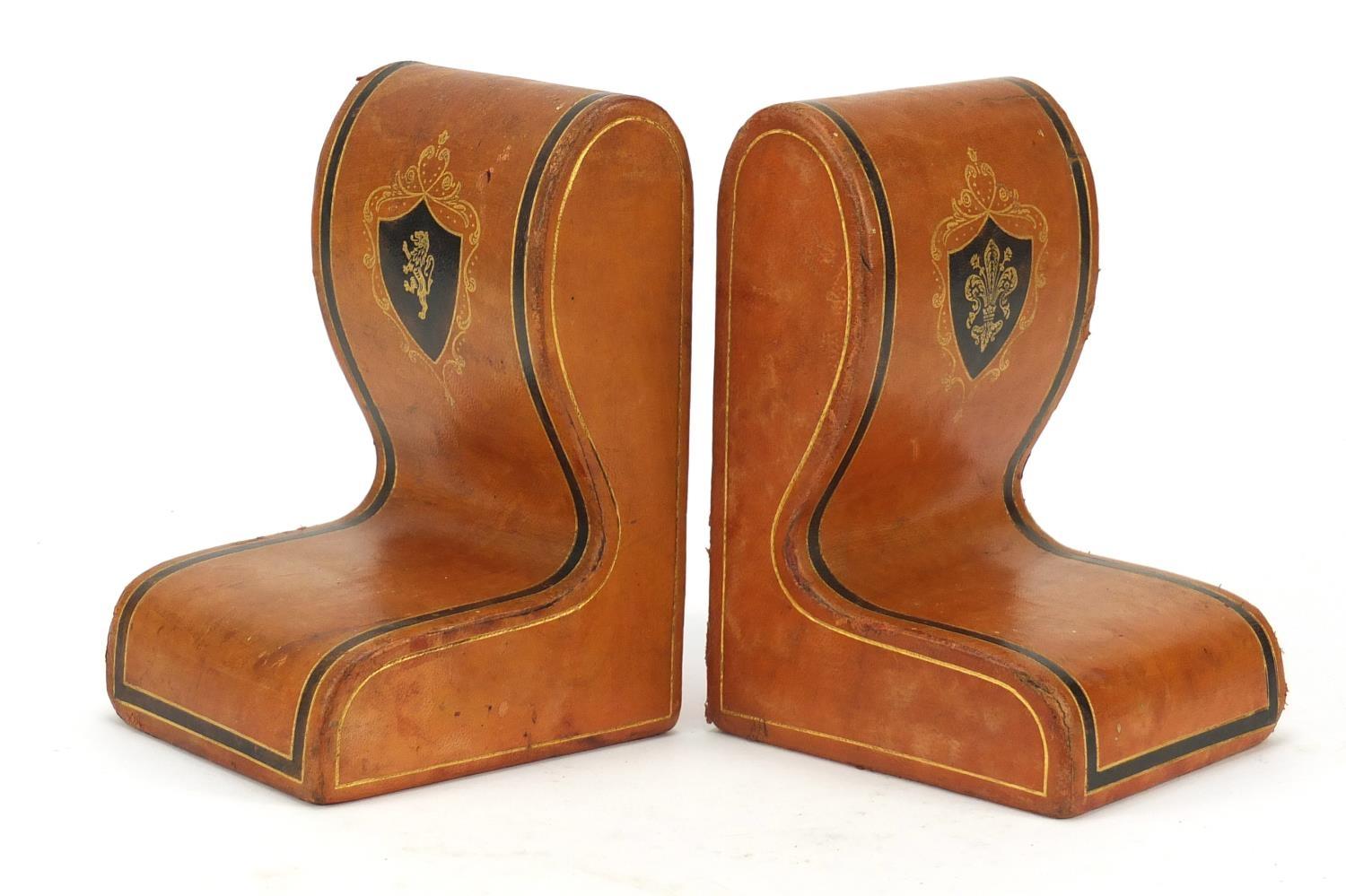 Pair of Italian tooled leather book ends with embossed crests, retailed by Harrods, each 17cm high :