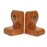 Pair of Italian tooled leather book ends with embossed crests, retailed by Harrods, each 17cm high :