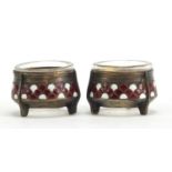 Pair of silver coloured metal and enamel salts with clear glass liners, impressed marks to the base,