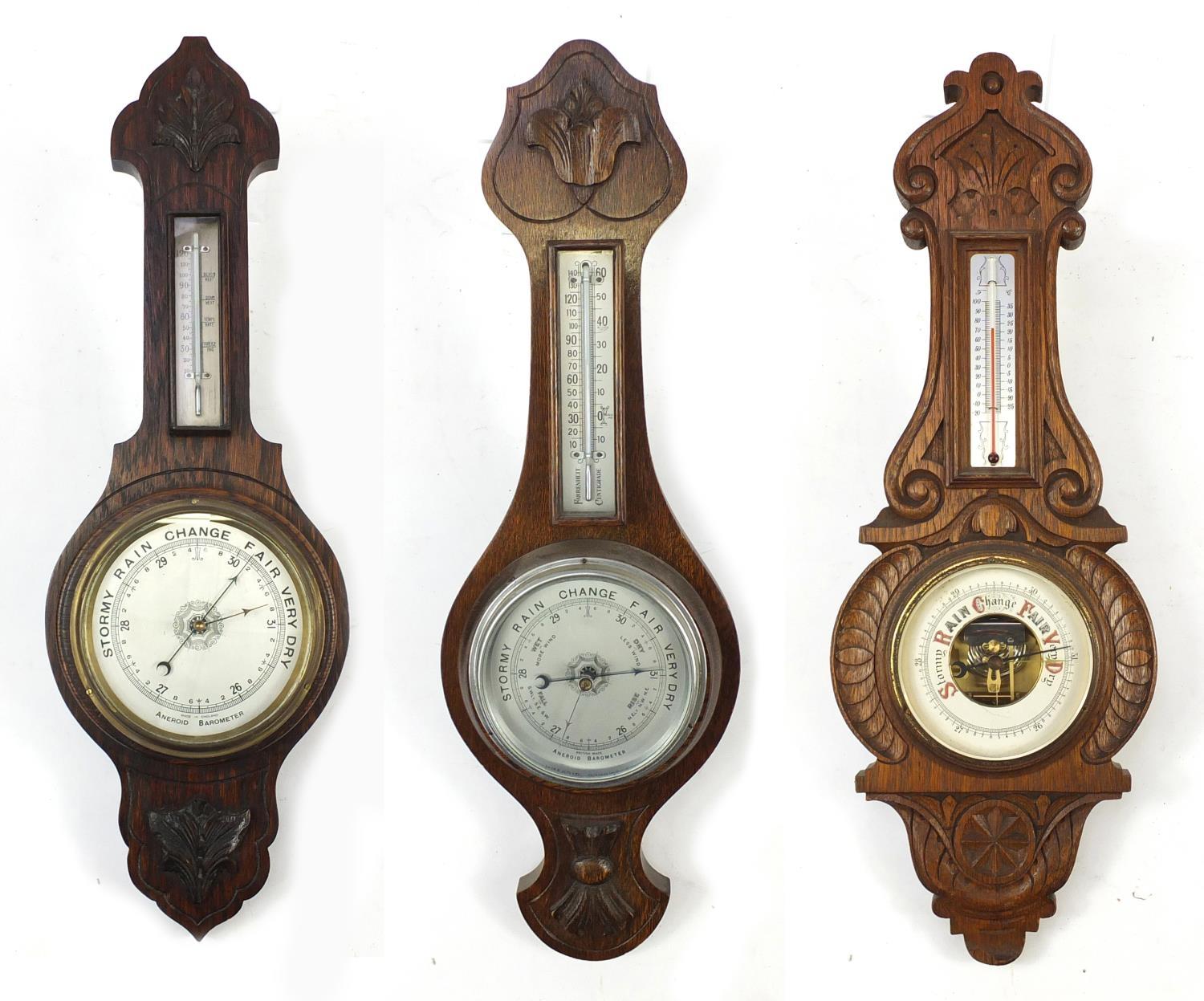 Three carved oak wall barometers and thermometers, two with silvered dials, the largest 66cm