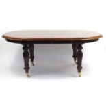 Mahogany wind out extending dining table, raised on baluster turned, fluted legs and brass casters