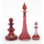 Three 19th century Bohemian ruby glass decanters comprising two with gilt foliate decoration and a