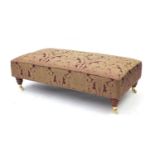Rectangular upholstered footstool on turned legs with brass caps and china casters, 34cm H x 110cm W