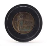 Military interest bronzed plaque housed in an ebonised frame, overall 12.5cm in diameter : For