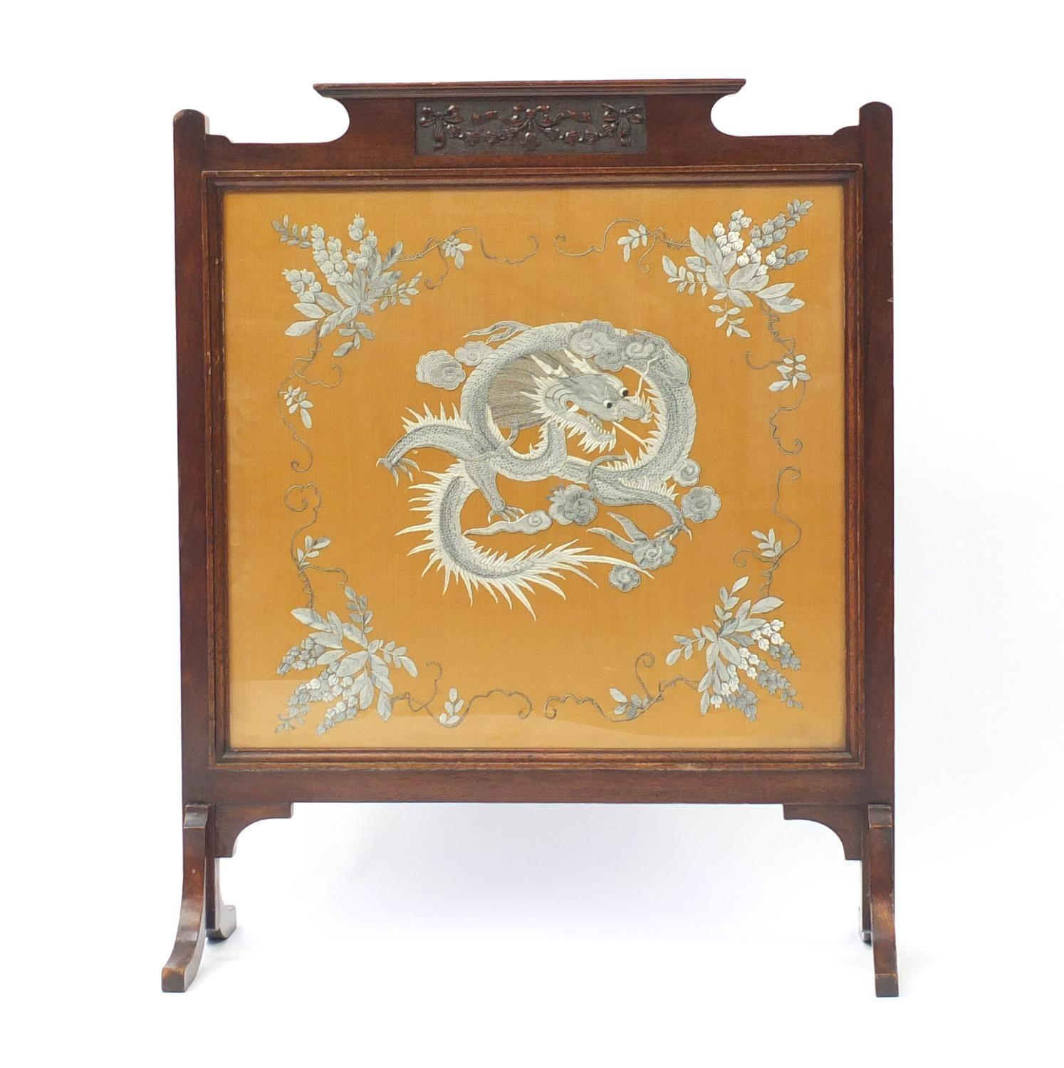 Chinese silk panel embroidered with a dragon and flowers, housed in a carved mahogany screen,