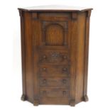Carved oak standing corner cabinet with pull down door above four drawers, 121cm H x 91cm W x 64cm D