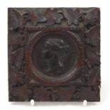 Victorian Madras Exhibition bronze medallion housed in a Black Forest frame carved with foliage,