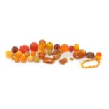 Group of amber coloured beads including one with a scorpion, the largest 5.2cm in length, 235.5g :