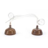 Two clear glass oral breast pumps mounted on turned wooden bases, the largest 32cm in length : For