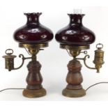 Pair of wooden oil lamps converted for electric use with ruby coloured glass shades, each 52cm