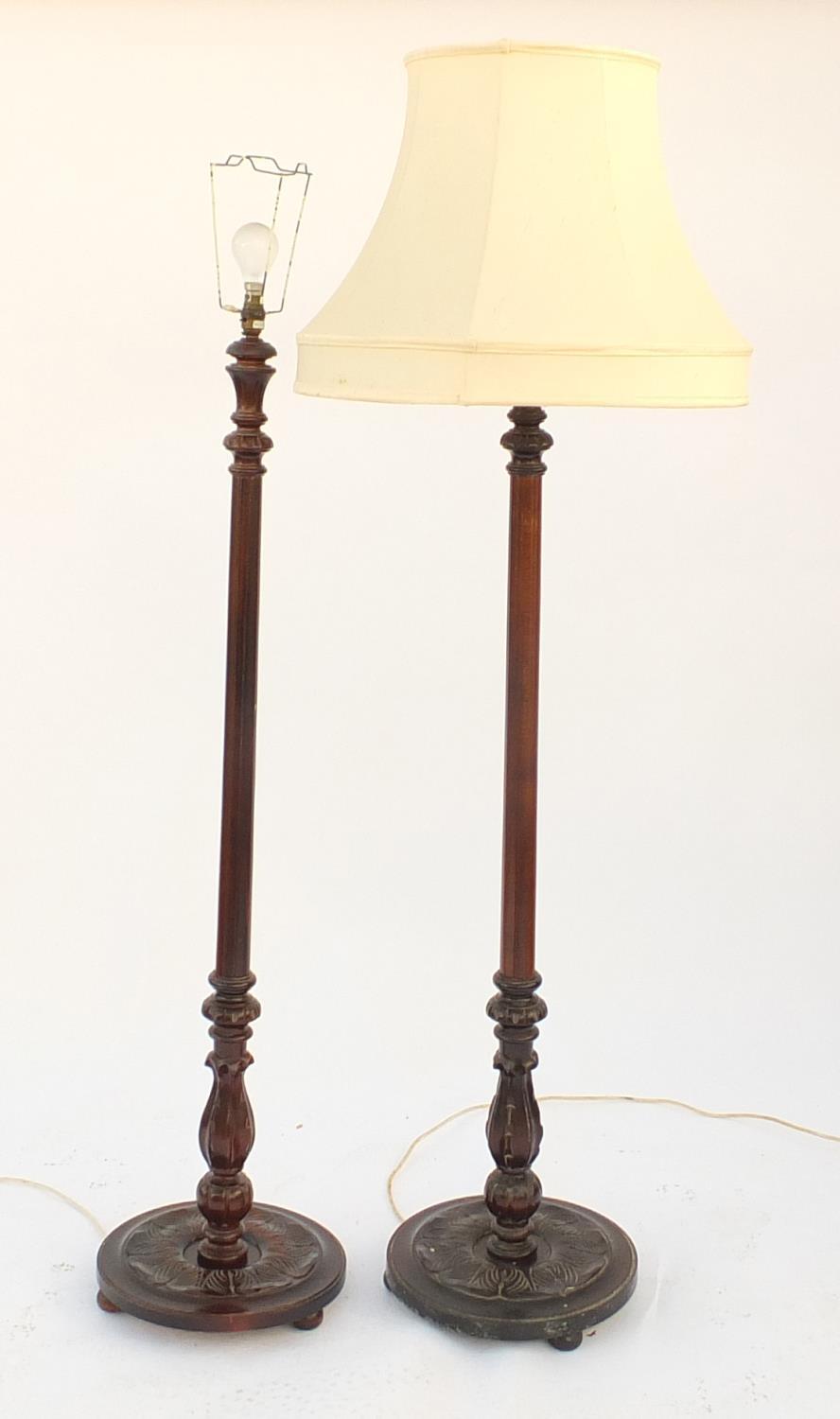 Pair of carved mahogany standard lamps, one with shade, each 130cm high excluding the fitting :