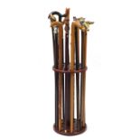 Sixteen walking sticks housed in a stick stand including some with brass animal heads and one with