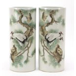 Pair of Chinese porcelain cylindrical vases hand painted with cranes amongst pine trees, 28.5cm high