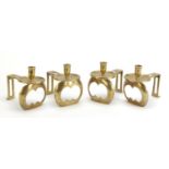 Manner of C F A Voysey, Set of four Arts & Crafts brass candlesticks, each 15cm in length