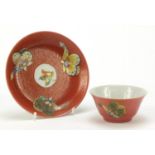 Chinese red ground porcelain tea bowl and saucer hand painted in the famille rose palette with