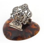 Silver coloured metal letter clip pierced with mermaids, raised on a tortoiseshell design base of