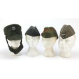 Three German military interest side caps and a field cap with badges