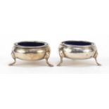 Pair of 18th century silver open salts raised on three hoof feet, with blue glass liners, A.L London