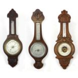 Three carved oak wall barometers and thermometers, two with silvered dials, the largest 66cm high
