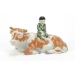 Chinese hand painted porcelain figure of a young child seated on a cow, 23cm in length