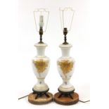Pair of white opaline glass vase lamps gilded with flowers raised on metal bases, each 60cm high