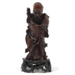 Chinese root wood carving of Shou Lou raised on a carved hardwood stand, 23.5cm high