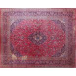 Rectangular Persian Kashan carpet with floral pattern onto a red and blue ground, 377cm x 295cm